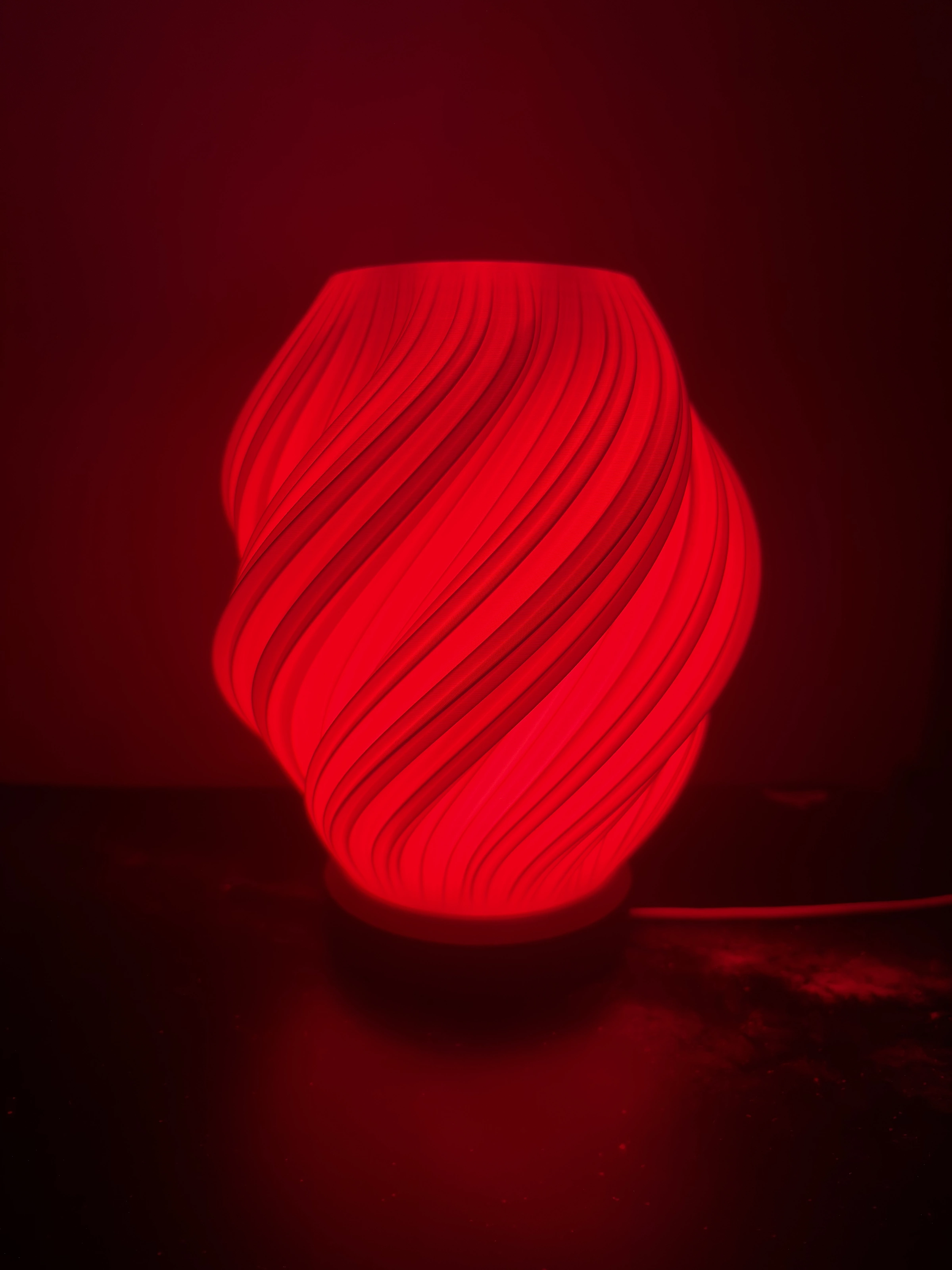 The Soft Star lamp lit deep red, filling the wall behind it with colour